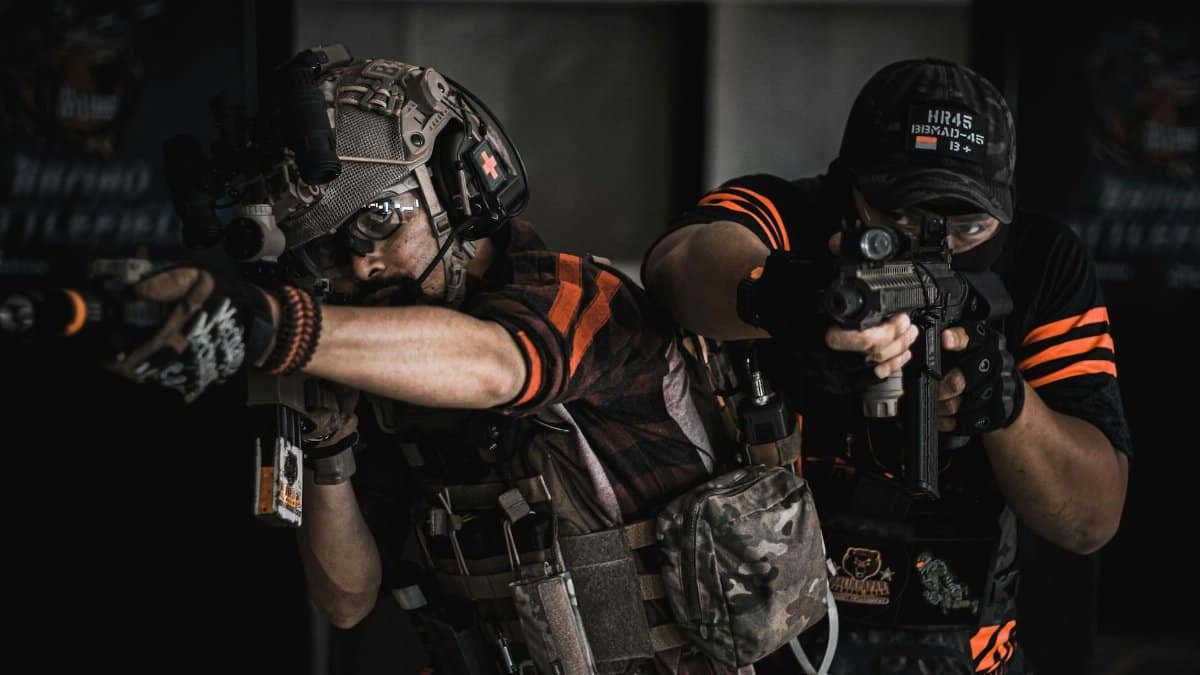 Two armed men in tactical gear engaging in realistic indoor combat training.
