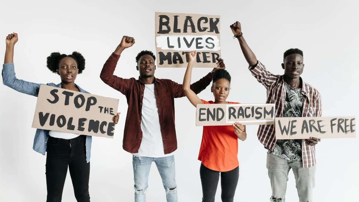 Group of people holding protest signs against racism and violence.
