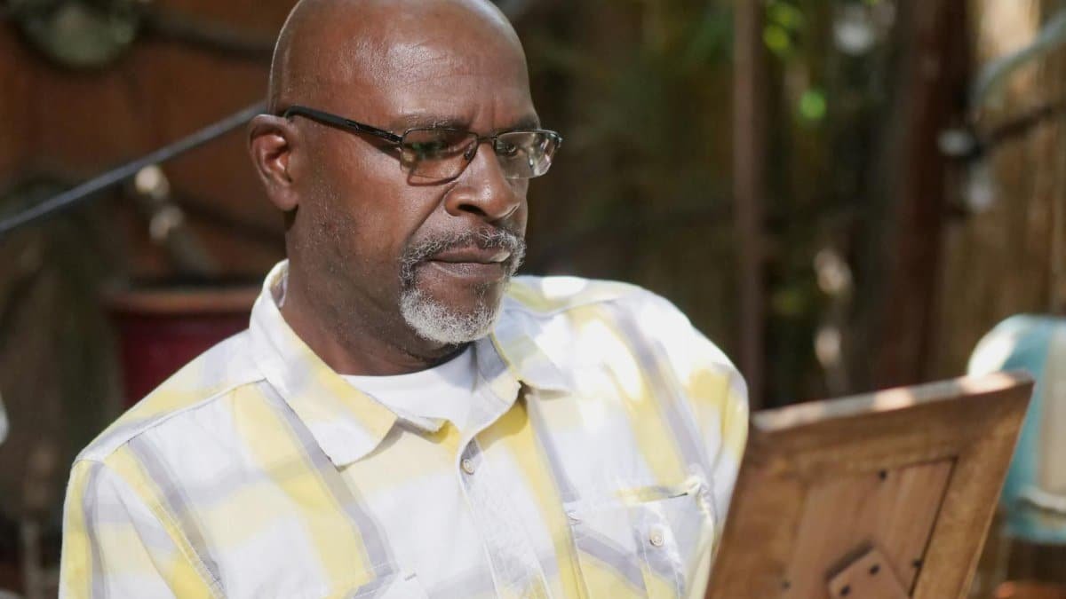 Senior man gazing at a photo frame, reflecting in a tranquil outdoor setting.