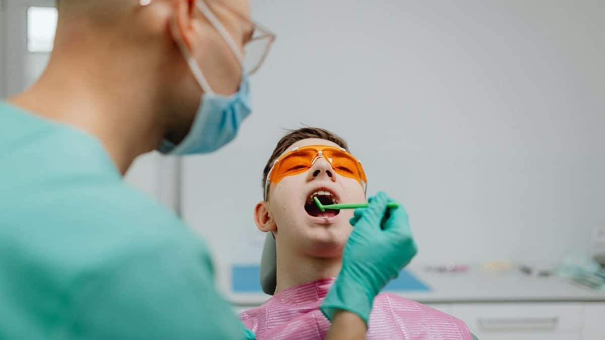 Dentist performing a dental checkup on a patient wearing protective eyewear.