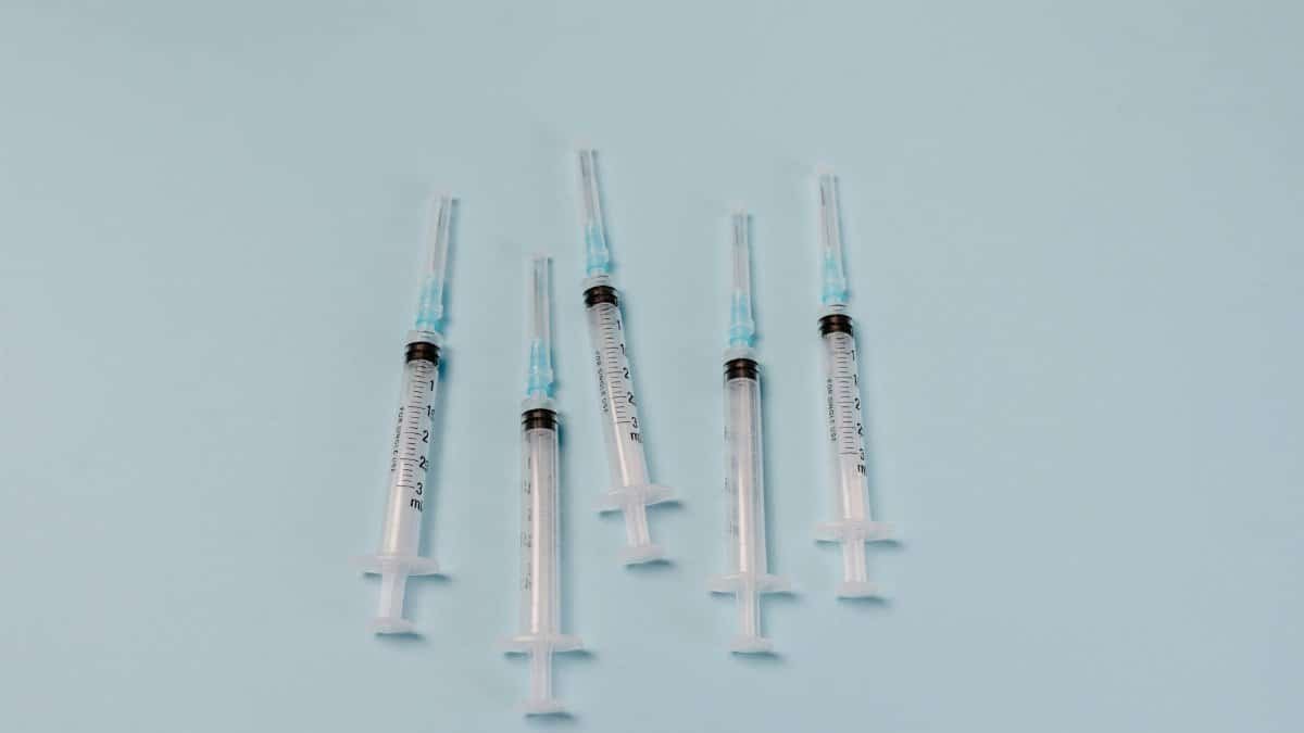 Close-up of sterile syringes arranged on a light blue surface, ideal for medical themes.