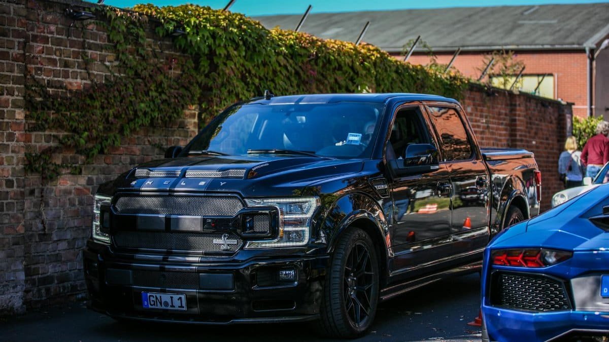 Stylish black pickup truck parked outdoors in a city setting with brick wall backdrop.
