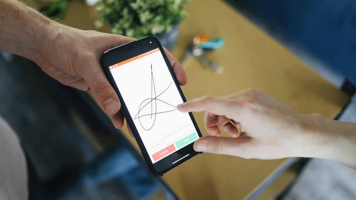 Two people completing a digital transaction with electronic signature on a smartphone screen.