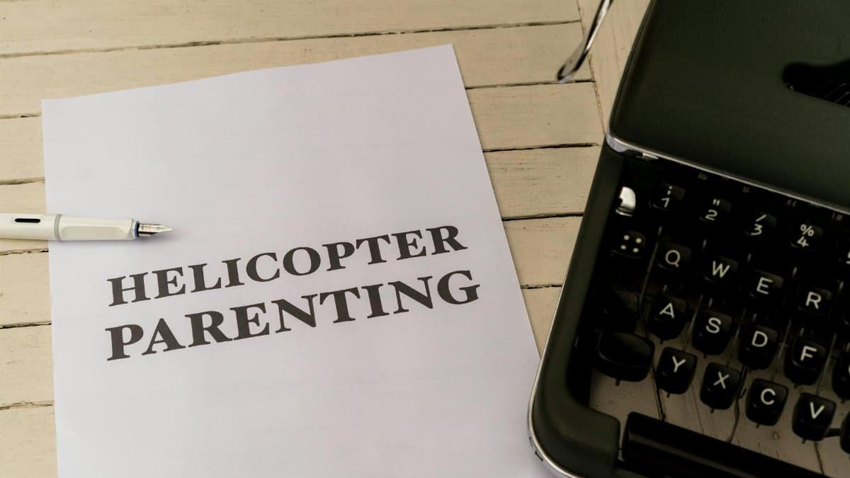 Paper with 'Helicopter Parenting' text next to a typewriter and pen