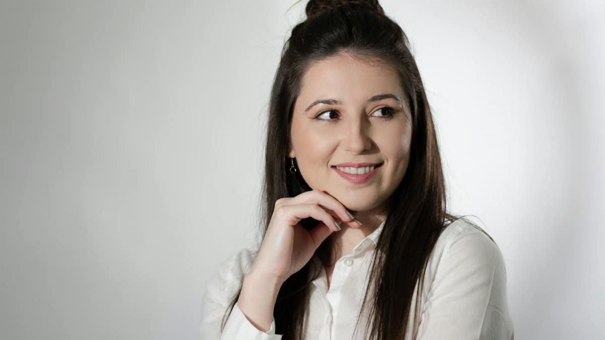 Professional portrait of a smiling woman in a white shirt, exuding confidence and friendliness.