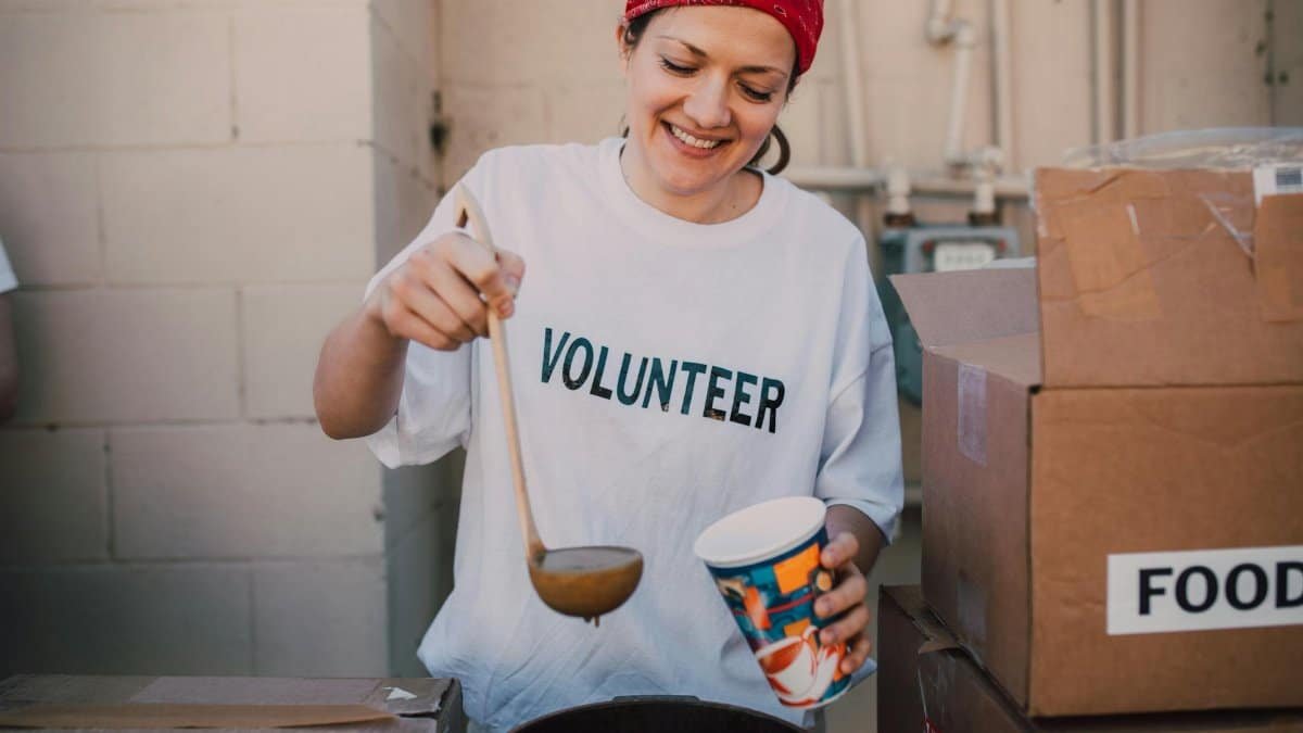 A cheerful volunteer serving food at a donation center, symbolizing generosity and community support.