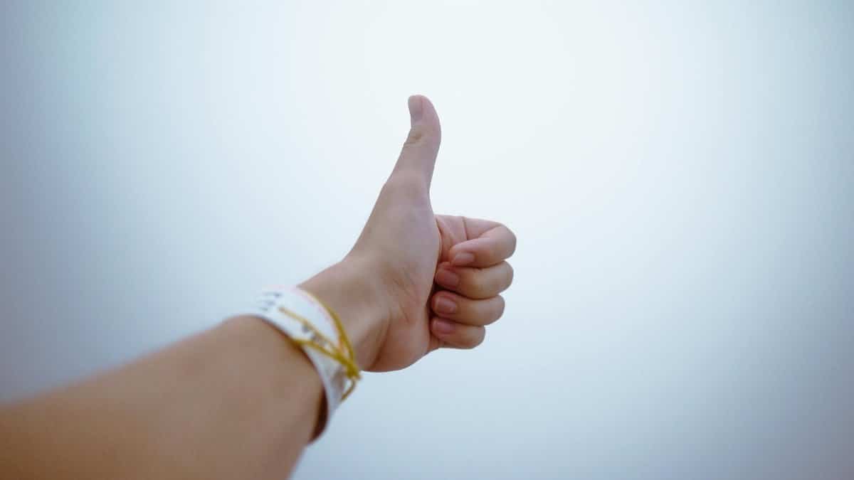 A hand giving a thumbs up gesture symbolizes approval and positivity.