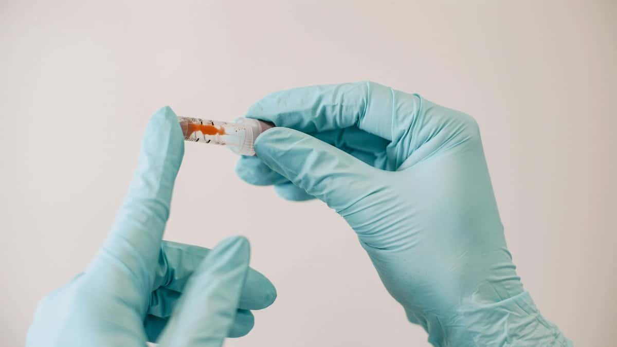 Close-up image of gloved hands holding a syringe in a sterile environment.
