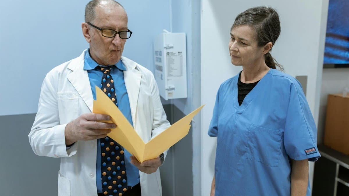 Doctors and nurses in consultation over patient records within a hospital setting.