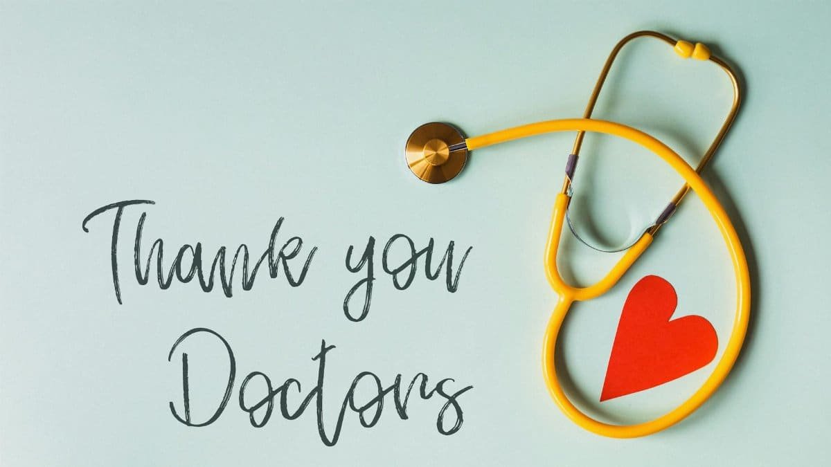 From above arrangement of yellow stethoscope with red heart shape placed on blue background with THANK YOU DOCTORS inscription