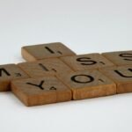 Close-up of Scrabble tiles spelling 'I Miss You' on a white surface with ample copy space.