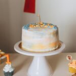 A beautifully decorated cake with cupcakes for a first birthday celebration.