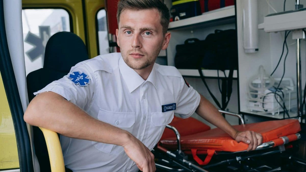 Male paramedic sitting inside an ambulance, ready for emergency response.
