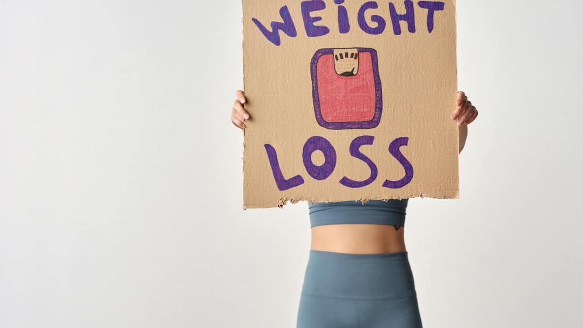 Person holding 'weight loss' sign for fitness motivation and health goals.