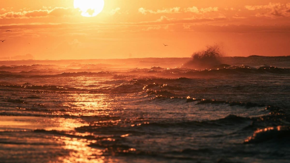Experience the serene beauty of ocean waves crashing under a stunning golden hour sunset.