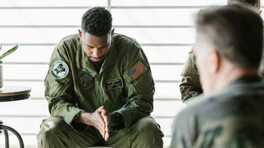 A soldier dressed in uniform sits pensively during a counseling session, embodying themes of mental health and support.