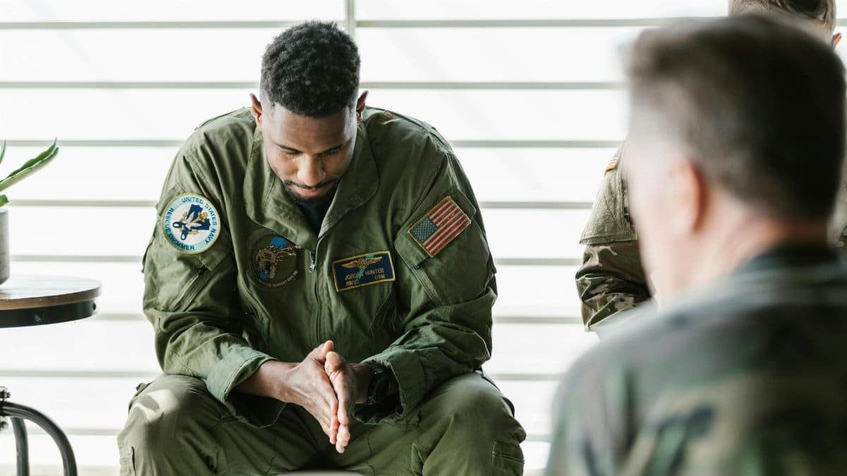 A soldier dressed in uniform sits pensively during a counseling session, embodying themes of mental health and support.