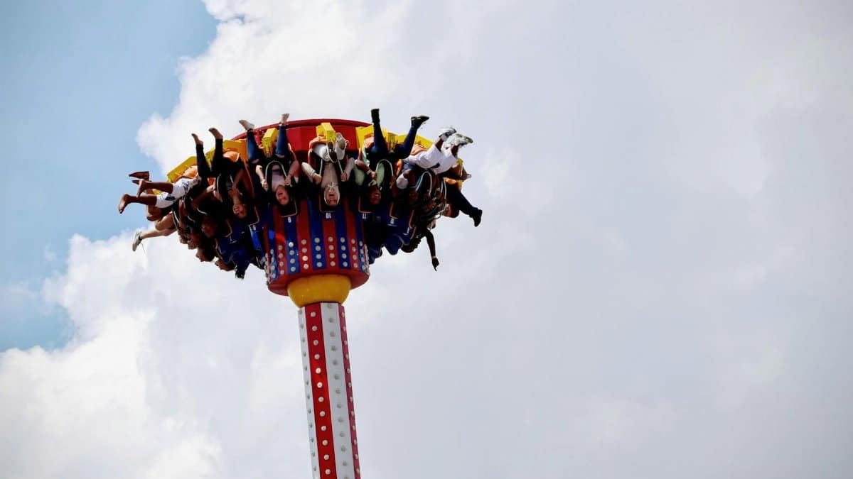 People enjoying an exhilarating amusement park ride against a cloudy sky backdrop.
