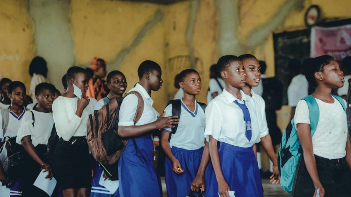 Group of African high school girls in uniform during class transition indoors.