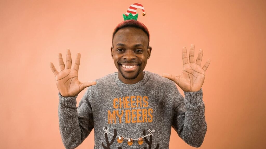 Portrait of a smiling man wearing a festive sweater and elf hat, spreading holiday cheer.
