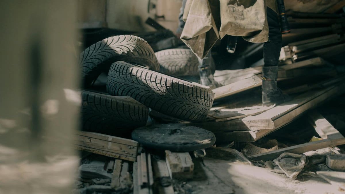 A gritty indoor shot of scattered tires and debris in an abandoned warehouse.