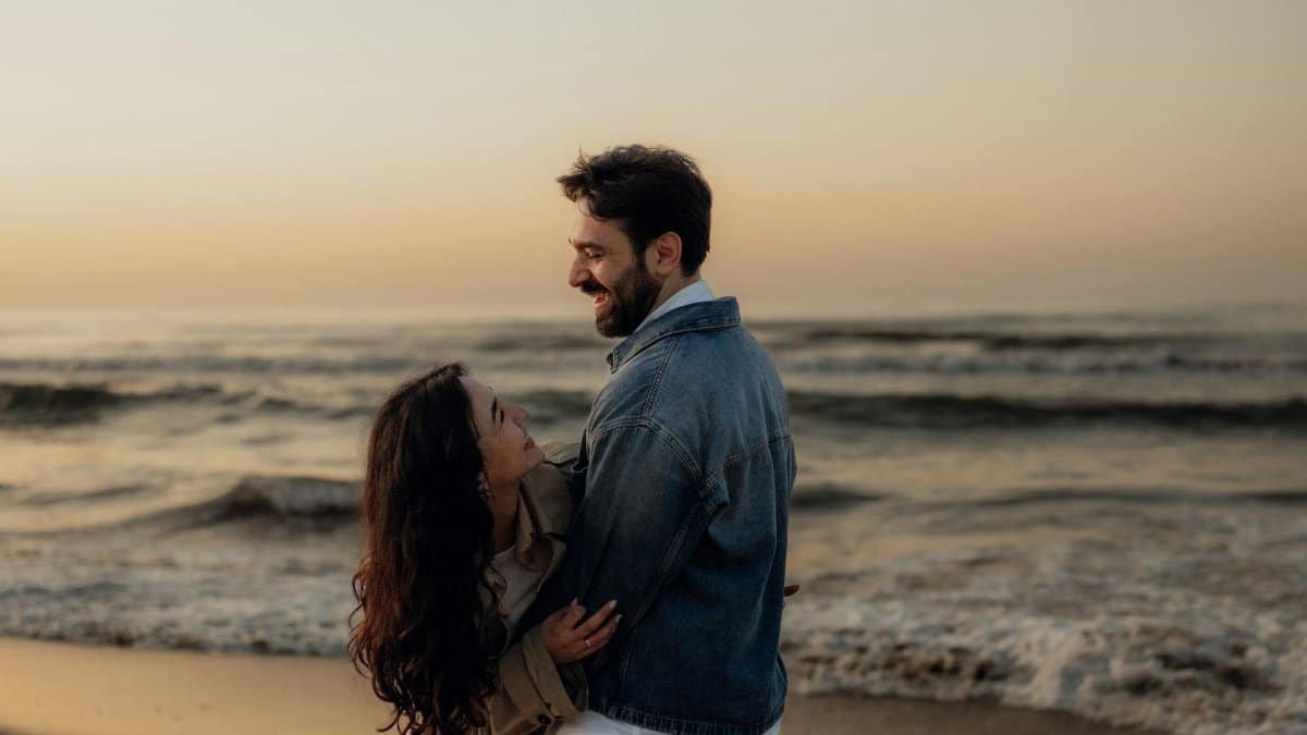 A loving couple embracing on a beach during a romantic sunset, enjoying the waves.