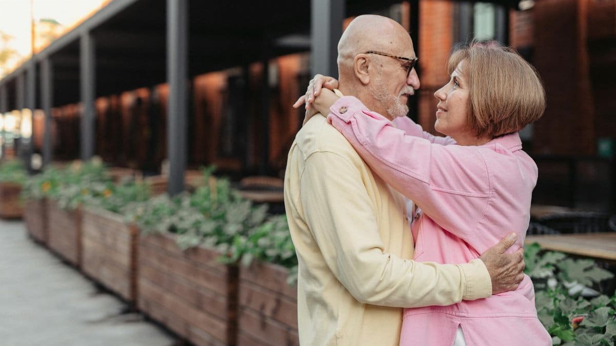 A loving elderly couple embracing outdoors, reflecting warmth and togetherness in an urban setting.