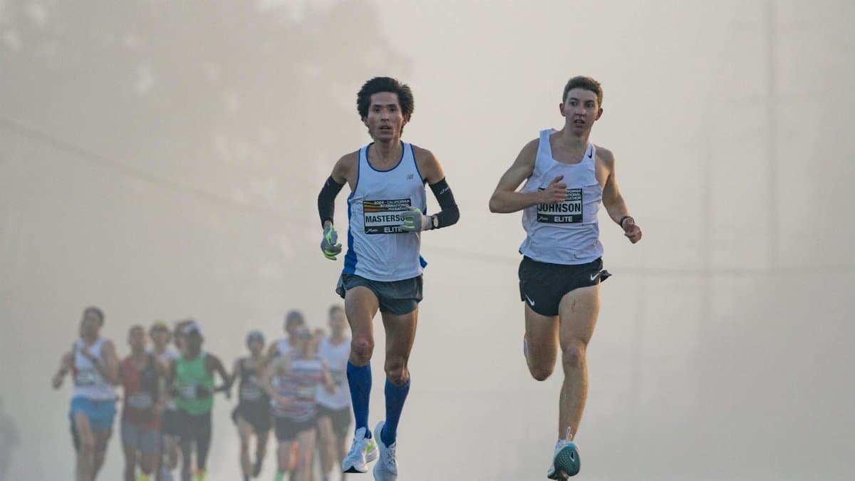Competitive marathon runners leading the pack on a foggy morning, showcasing endurance and determination.