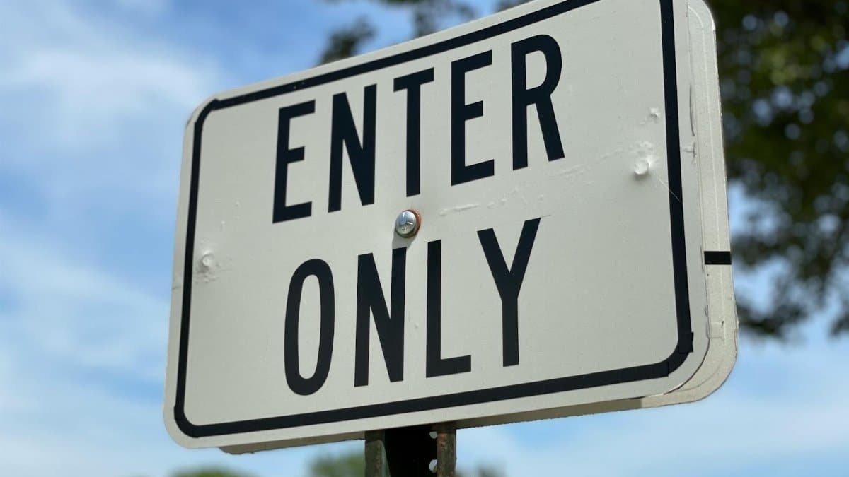 A close-up image of an 'Enter Only' road sign against a clear blue sky.