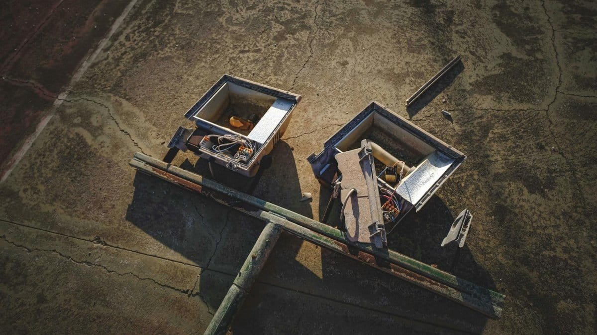 High angle view of discarded electronics with exposed wires and components on a cracked surface.