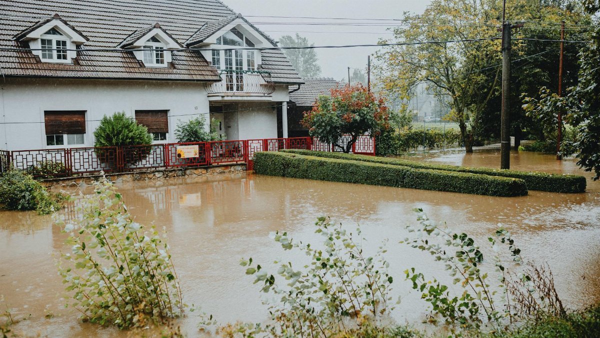 A suburban house surrounded by floodwaters after heavy rain, showing impact of natural disaster.