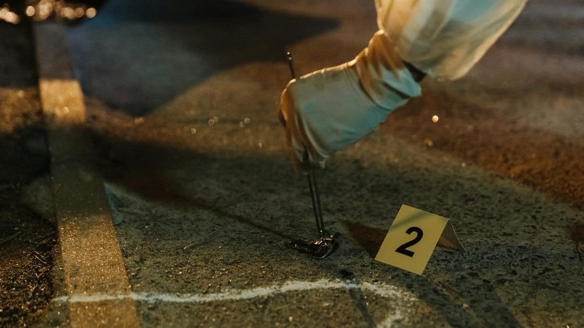 Close-up of a forensic investigator collecting evidence at a night crime scene with gloved hands.