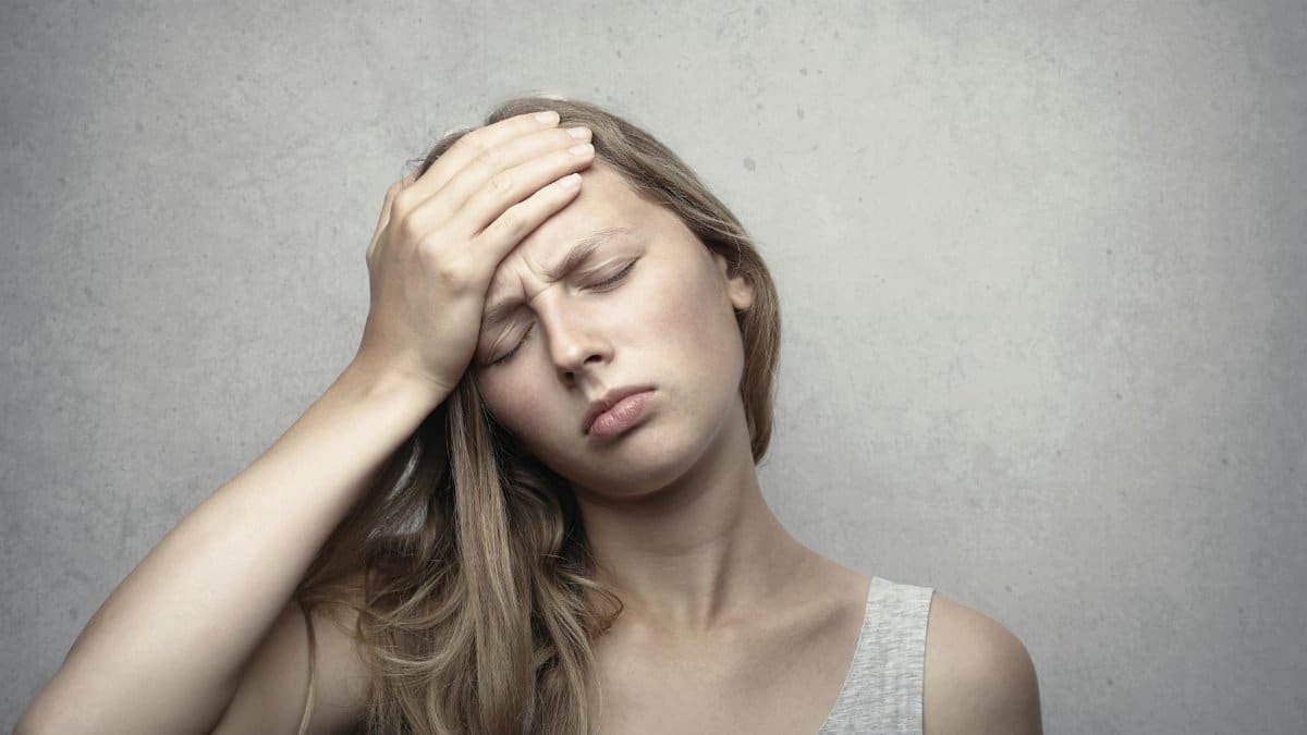 A woman in distress holding her head, expressing emotion and fatigue.