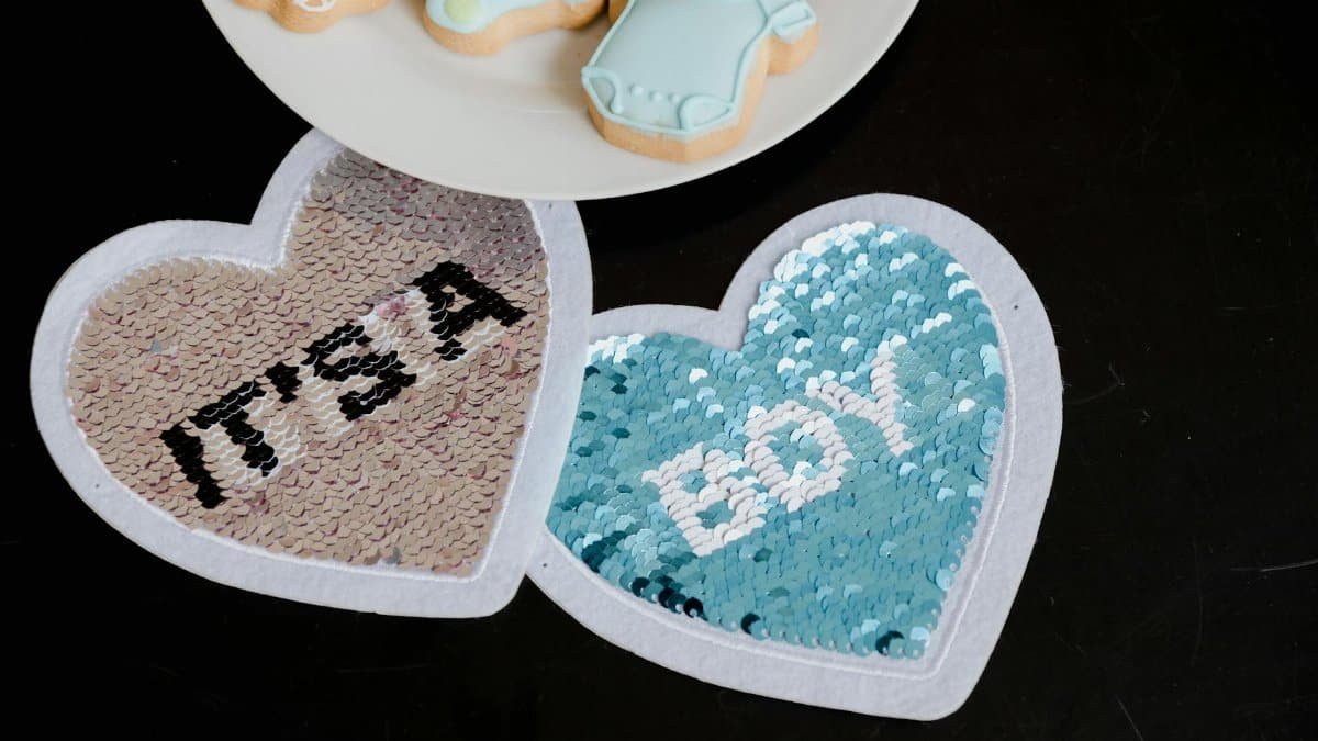 Heart-shaped 'It's a Boy' sequined decor with cookies for a gender reveal party. Ideal for celebrations.