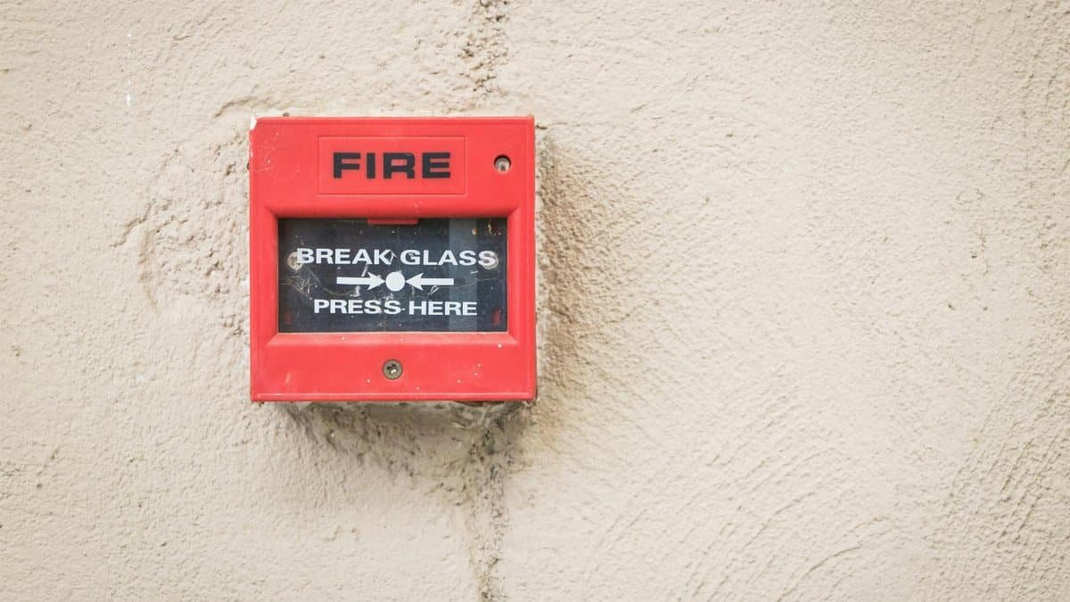 Close-up of a red fire alarm mounted on a textured wall, ready for emergency use.