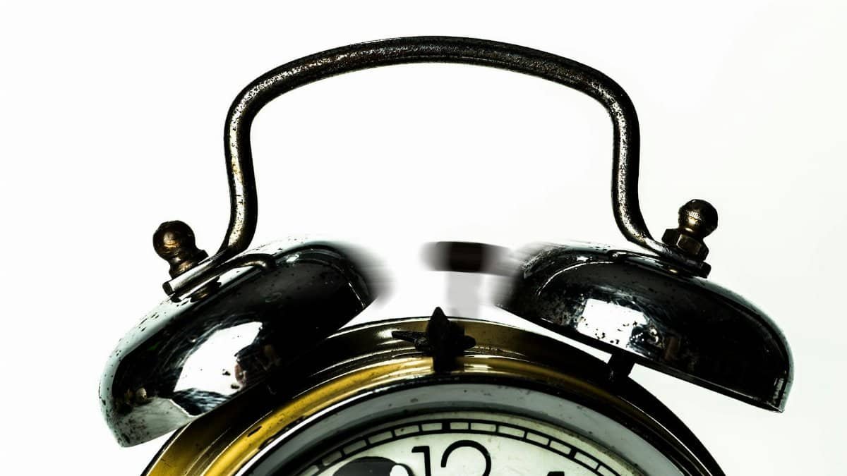 Close-up of a classic vintage alarm clock with ringing bells on a white background.