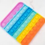 Rainbow Pop It fidget toy on a bright white surface, perfect for stress relief.