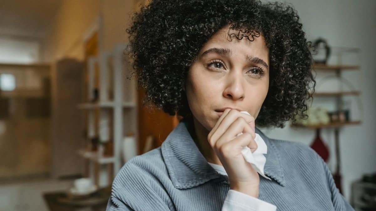 Portrait of a young woman with curly hair expressing sadness indoors.