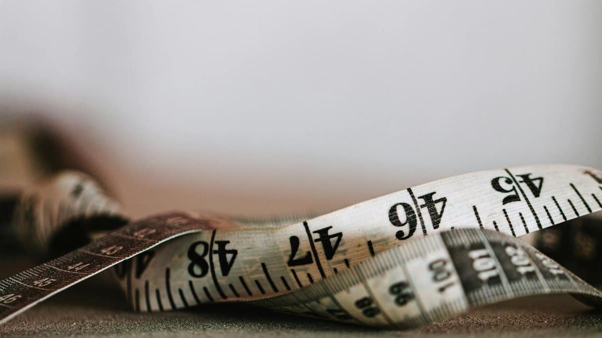 Extreme close-up shot of a coiled measuring tape showing numbers in inches and centimeters.