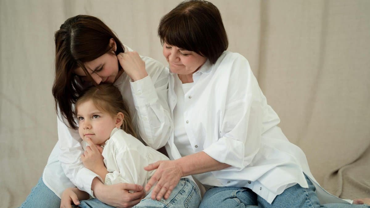 Heartwarming scene of three generations bonding in cozy jeans and white shirts, showcasing family love.