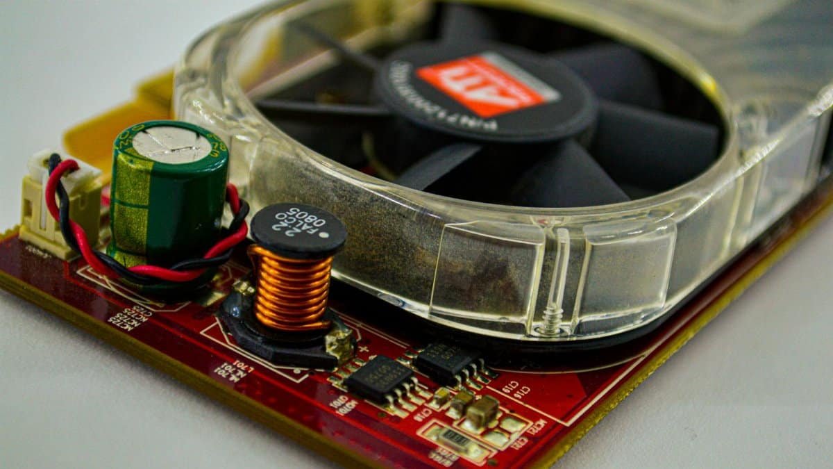 Detailed view of a cooling fan and capacitor on a computer circuit board, showcasing electronic components.