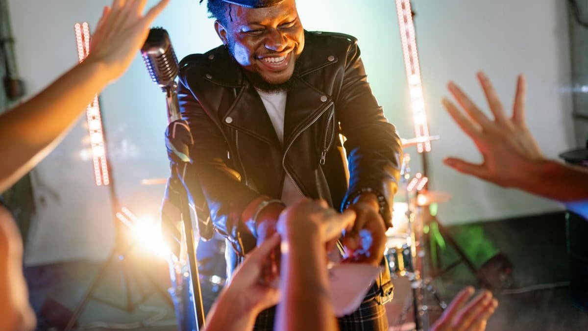 Smiling musician interacts with fans during a live performance, creating a captivating atmosphere.