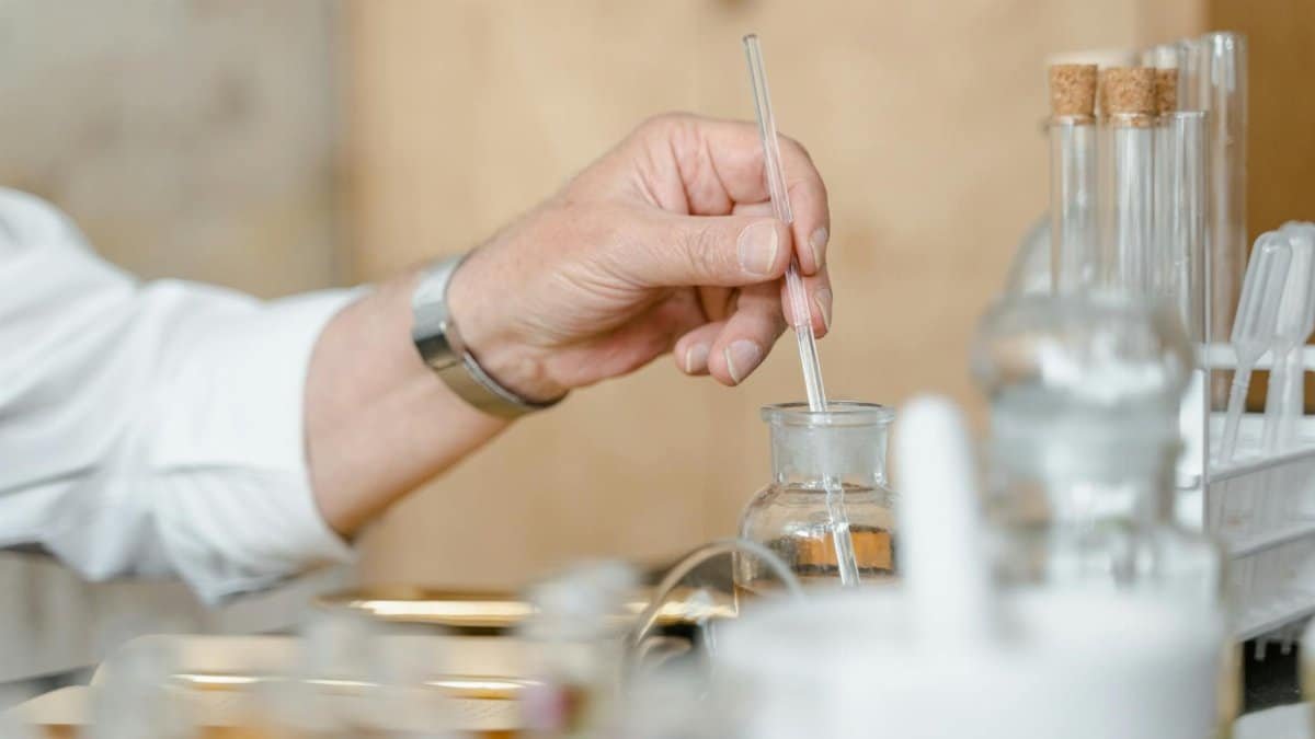 Close-up of a person mixing chemicals in a laboratory with glassware.