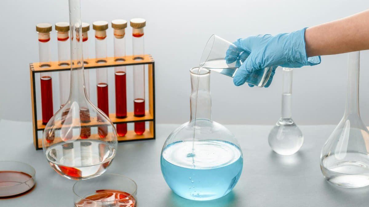 Close-up of scientist pouring liquid into a flask in a laboratory setting