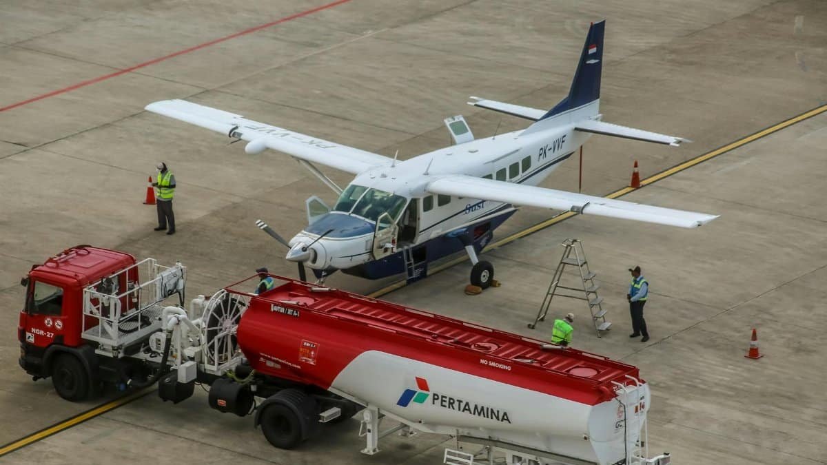 A small aircraft being refueled on an airport tarmac with workers present.