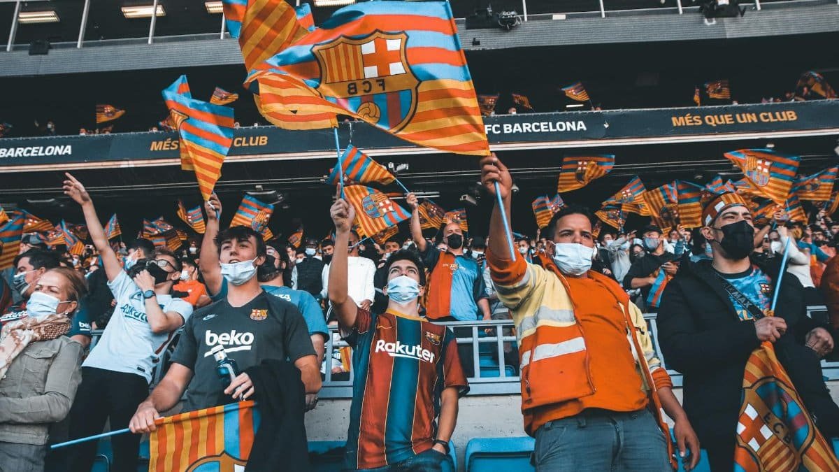 Fans enthusiastically wave FC Barcelona flags at a football match, showcasing team spirit and unity.