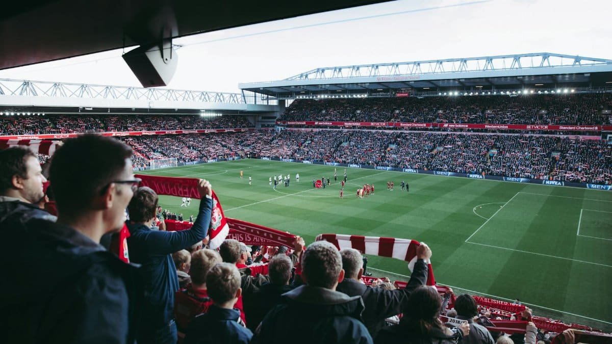 Fans cheer as players take the field at a vibrant football stadium, creating an electric atmosphere.