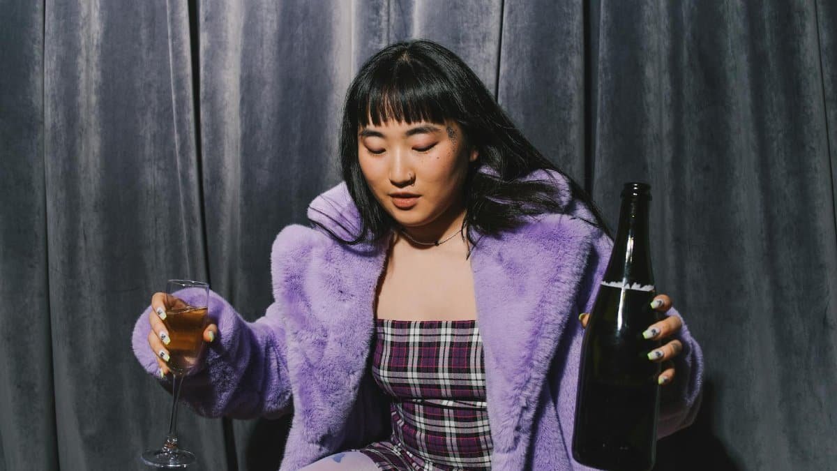 Asian woman in purple fur coat enjoying New Year celebration with wine.