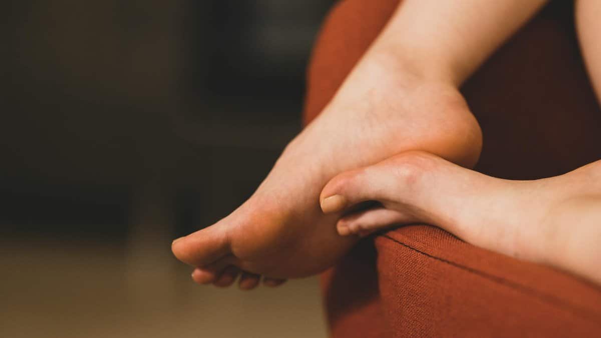 A serene close-up of feet resting on a cozy red sofa indoors, depicting relaxation.