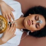 A woman meditates with a Tibetan singing bowl and crystals, promoting wellness and spiritual healing.